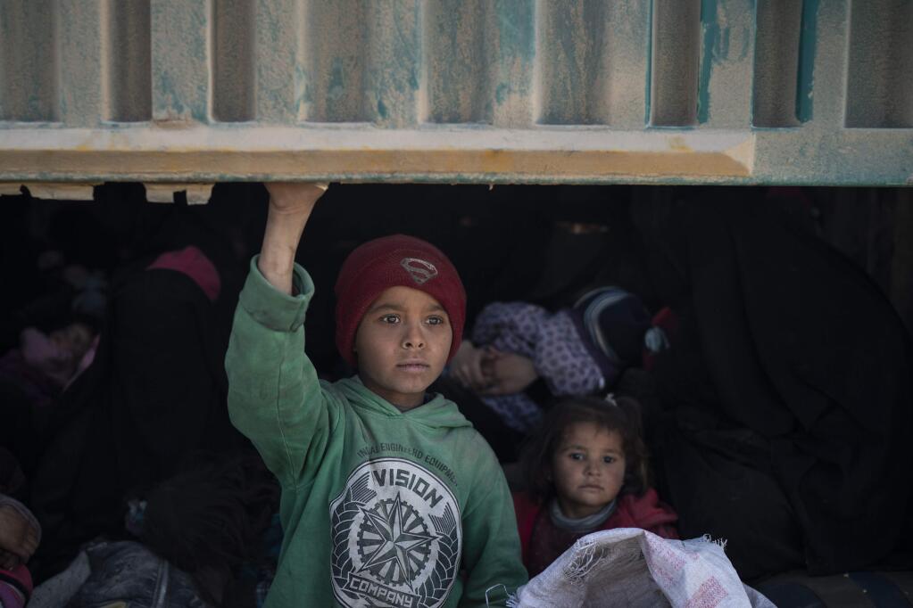 Children ride in the back of a truck that is part of a convoy evacuating hundreds out of the last territory held by Islamic State militants, in Baghouz, eastern Syria, Wednesday, Feb. 20, 2019. The evacuation signals the end of a week long standoff and opens the way to U.S.-backed Syrian Democratic Forces (SDF) recapture the territory. (AP Photo/Felipe Dana)