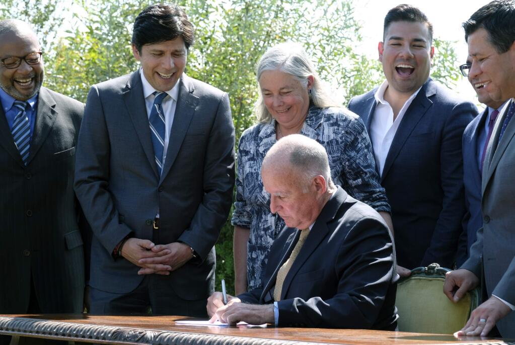California Gov. Jerry Brown, seated, signs legislation while joined by Senate President pro tempore Kevin de Leon, D-Los Angeles, second from left, and state Sen. Fran Pavley, D-Agoura Hills, Thursday, Sept. 8, 2016, in Los Angeles. The law sets a new goal to reduce greenhouse gas emissions 40 percent below 1990 levels by 2030. (AP Photo/Richard Vogel)
