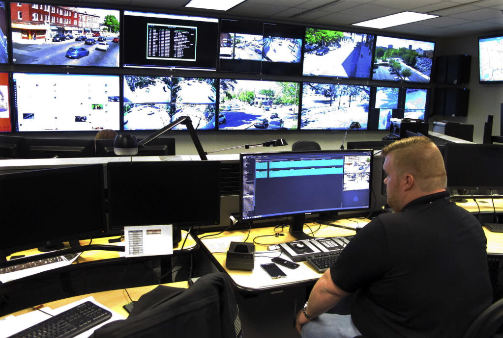 FILE - In this May 20, 2016, file photo, Tyler Cullen, of Vulcan Security Technologies, looks at video screens in the Hartford police Real-Time Crime and Data Intelligence Center in Hartford, Conn. Police in Hartford are facing a complaint by the Connecticut ACLU to the state public records commission for not releasing information about analytical software for the city's surveillance camera system that officials say will help predict crime and capture suspects. (AP Photo/Dave Collins, File)
