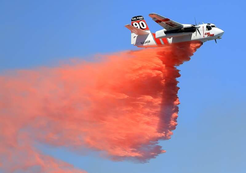 A Cal Fire air tanker drops retardant on a brush fire at the old county landfill in Healdsburg, Tuesday June 18, 2013. (Kent Porter / Press Democrat) 2013