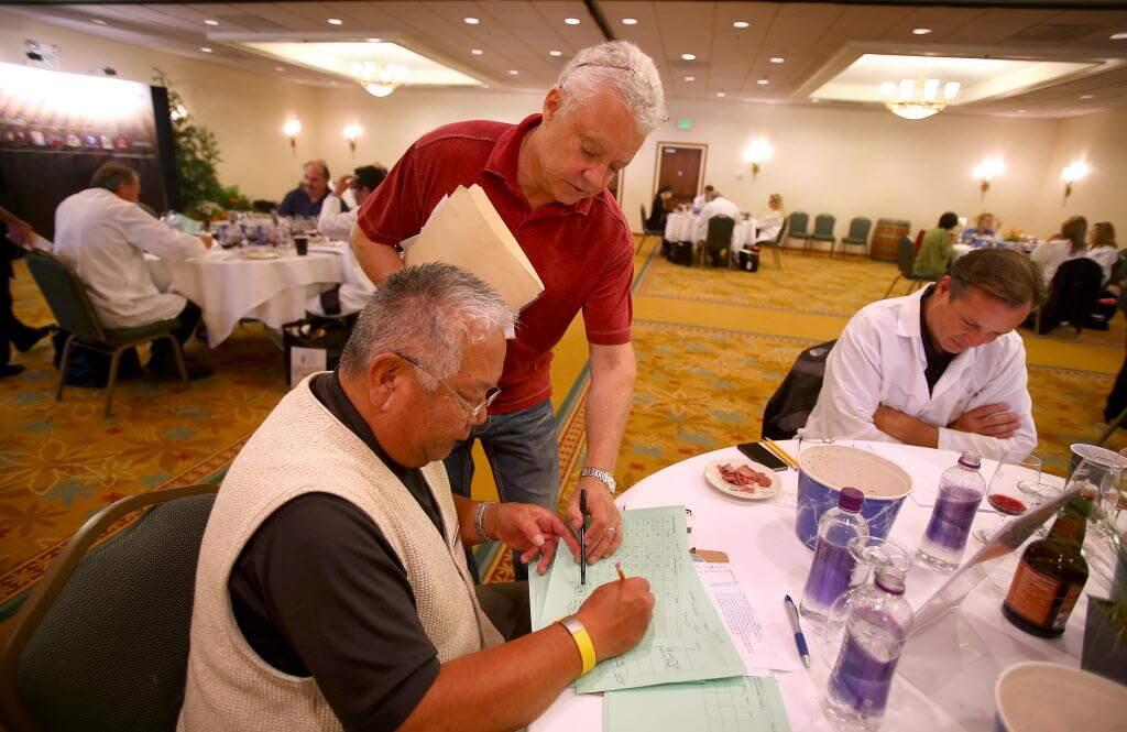 Christopher Chung / The Press Democrat, 2014Daryl Groom, standing, goes over a judging form with table monitor Doug Uyehara during the North Coast Wine Challenge.