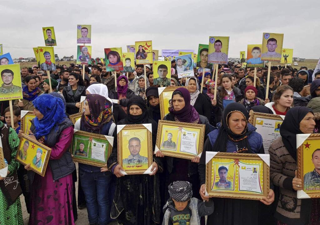 This photo provided by Ronahi TV, a Kurdish television channel, that is consistent with independent AP reporting, shows Kurdish protesters holding portraits of loved ones who died fighting the Islamic State group, during a protest outside a U.S.-led coalition base, in Jalabiya village, southeast of Kobani, Syria, Thursday, Dec. 20, 2018. Thousands of Syrians have gathered to protest Turkish threats of an imminent offensive. (Ronahi TV via AP)