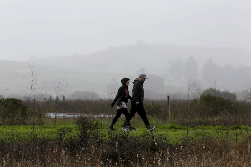 Vanessa Santana and her husband Thorsten Gorny walk through a light rain shower at Shollenberger Park on Sunday, February 3, 2019 in Petaluma, California . (BETH SCHLANKER/The Press Democrat)