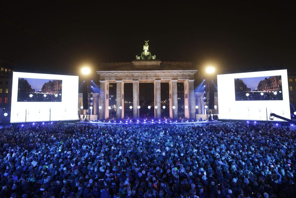 Thousands of people gather in front of Brandenburg Gate during the central event commemorating the fall of the wall in Berlin, Germany, Sunday, Nov. 9, 2014. 25 years ago - on Nov. 9, 1989 - the East-German government lifted travel restrictions and thousands of East Berliners had pushed their way past perplexed border guards to celebrate freedom with their brethren in the West. (AP Photo/Michael Sohn)