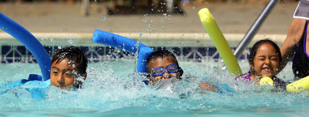 Trigo Castellanos, 9, Adan Velasquez, 7 and Brisa Hernandez, 5, race across the Cloverdale YMCA pool on their pool noodles at the end of their swimming lessons in the 'Vamos a Nadar' program on Saturday, July 8, 2017. (John Burgess/The Press Democrat)