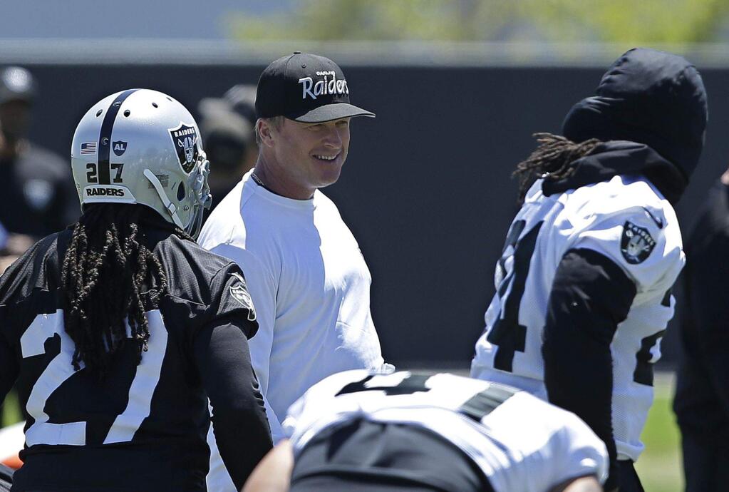 Oakland Raiders coach Jon Gruden smiles as he talks with running back Marshawn Lynch, right at the NFL football team's minicamp Wednesday, June 13, 2018, in Alameda, Calif. (AP Photo/Rich Pedroncelli)