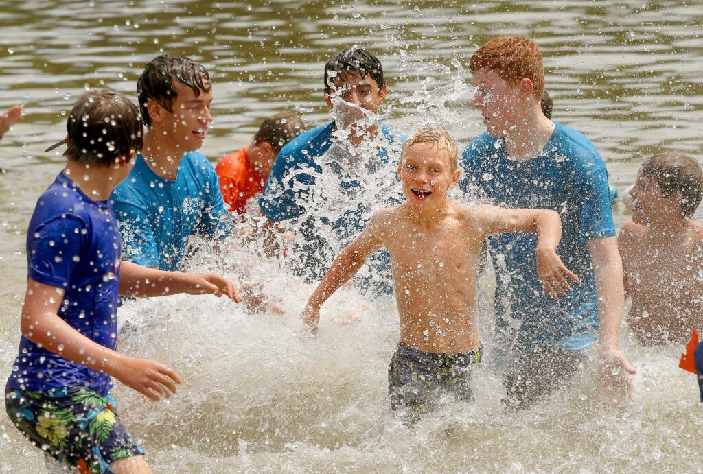 Drew Bashiell, 9, runs away from the splashing Camp Wa-Tam counselors-in-training on Tuesday while swimming at the Spring Lake lagoon. (JOHN BURGESS/The Press Democrat)