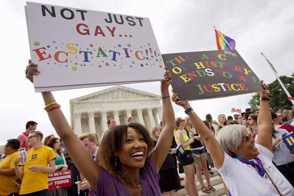 Ikeita Cantu, left, and her wife Carmen Guzman, of McLean, Va., hold up signs as they celebrate outside of the Supreme Court in Washington, Friday June 26, 2015, after the court declared that same-sex couples have a right to marry anywhere in the US. The couple was married in Canada in 2009 when gay marriage was illegal in Virginia. (AP Photo/Jacquelyn Martin)