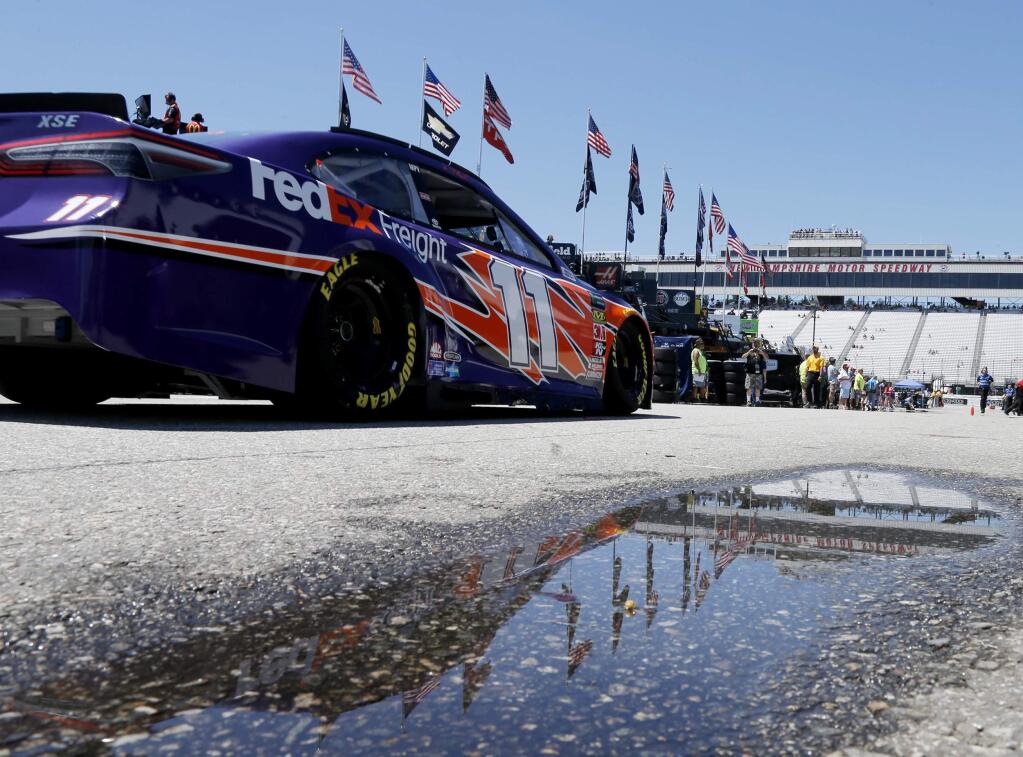 NASCAR Cup Series driver Denny Hamlin drives past a puddle reflecting the grandstands during practice Friday, July 20, 2018, at New Hampshire Motor Speedway in Loudon, N.H. Rain is in the forecast for Sunday's race. (AP Photo/Mary Schwalm)