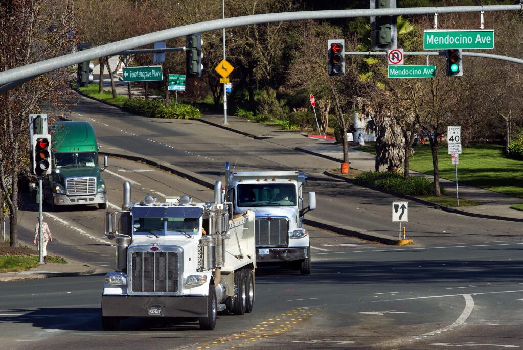 Debris trucks head down the Fountain Grove Parkway, one day after a dump truck lost control and crashed into nine cars at the intersection of Fountain Grove and Mendocino Avenue. (JOHN BURGESS / The Press Democrat)