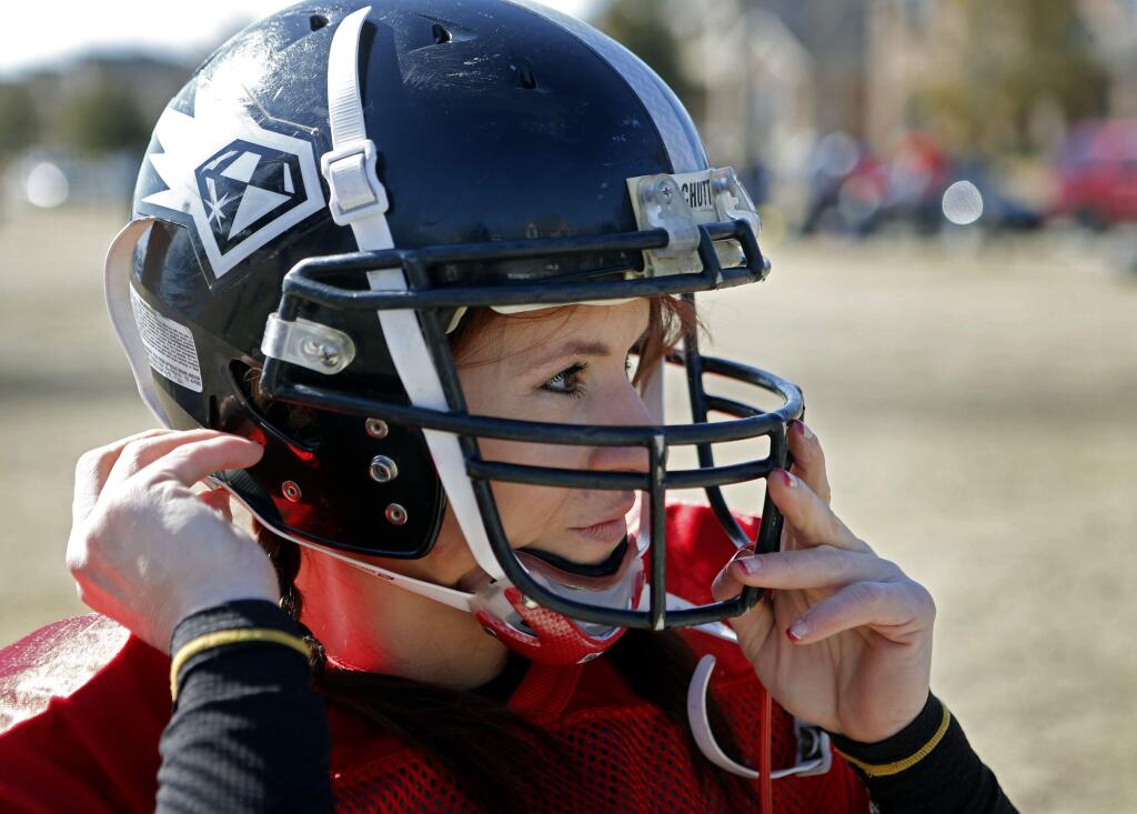 In this Feb. 12, 2014, photo, Jen Welter puts her helmet on before the start of the Texas Revolution practice at Bradford Crossing Park in Allen, Texas. The Arizona Cardinals have hired Welter to coach inside linebackers through their upcoming training camp and preseason. (Vernon Bryant/The Dallas Morning News via AP)