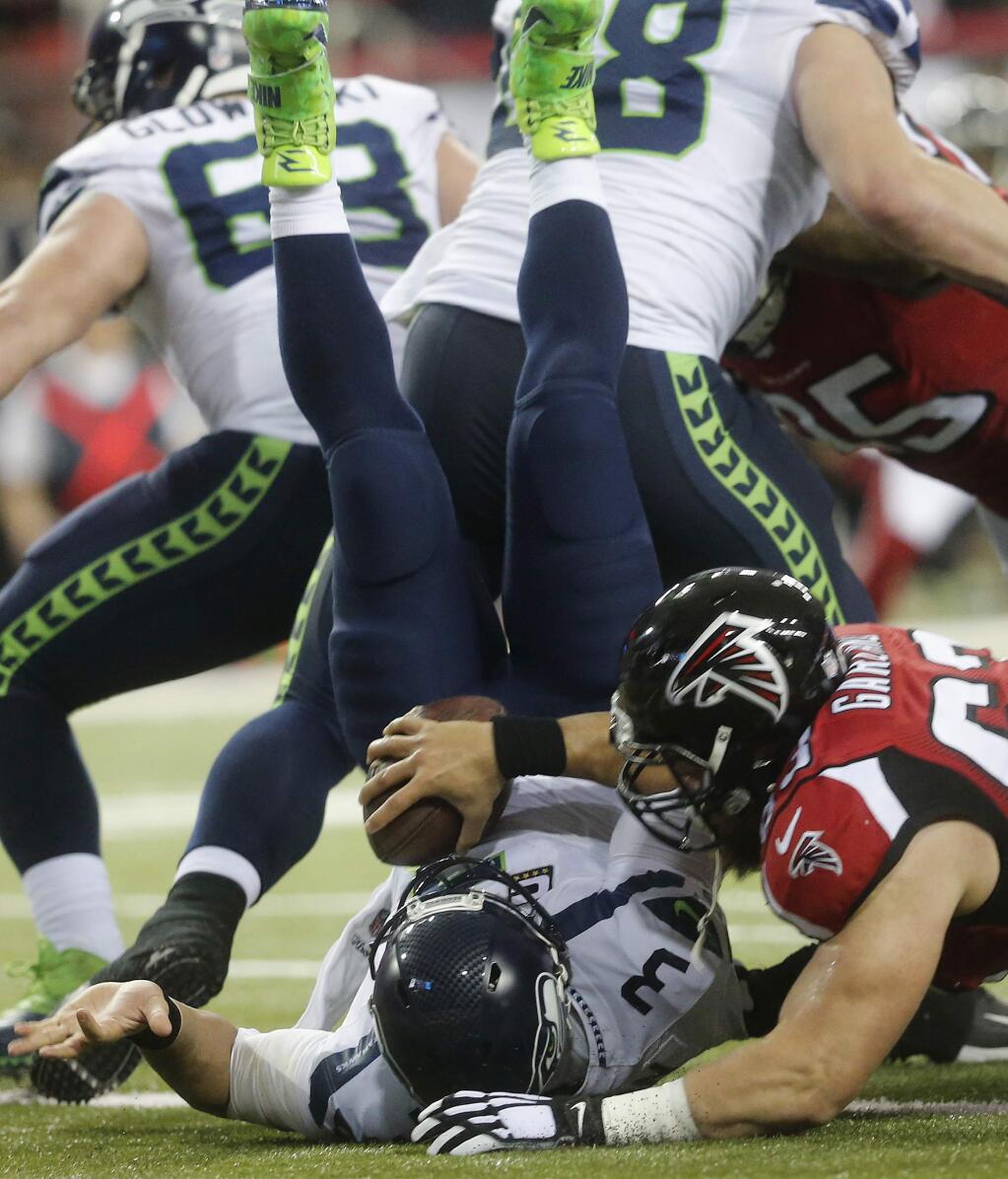 Atlanta Falcons' Ben Garland (63) falls onto Seattle Seahawks quarterback Russell Wilson (3) for a Falcons safety during the first half of an NFL football divisional football game, Saturday, Jan. 14, 2017, in Atlanta. (AP Photo/John Bazemore)