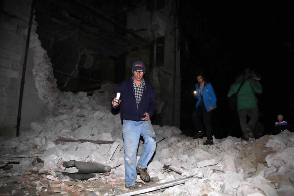 Residents walk past rubble in the village of Visso, central Italy, Wednesday, Oct. 26, 2016 following an earthquake. A pair of powerful aftershocks shook central Italy on Wednesday, knocking out power, closing a major highway and sending panicked residents into the rain-drenched streets just two months after a powerful earthquake killed nearly 300 people. (Matteo Crocchioni/ANSA via AP)