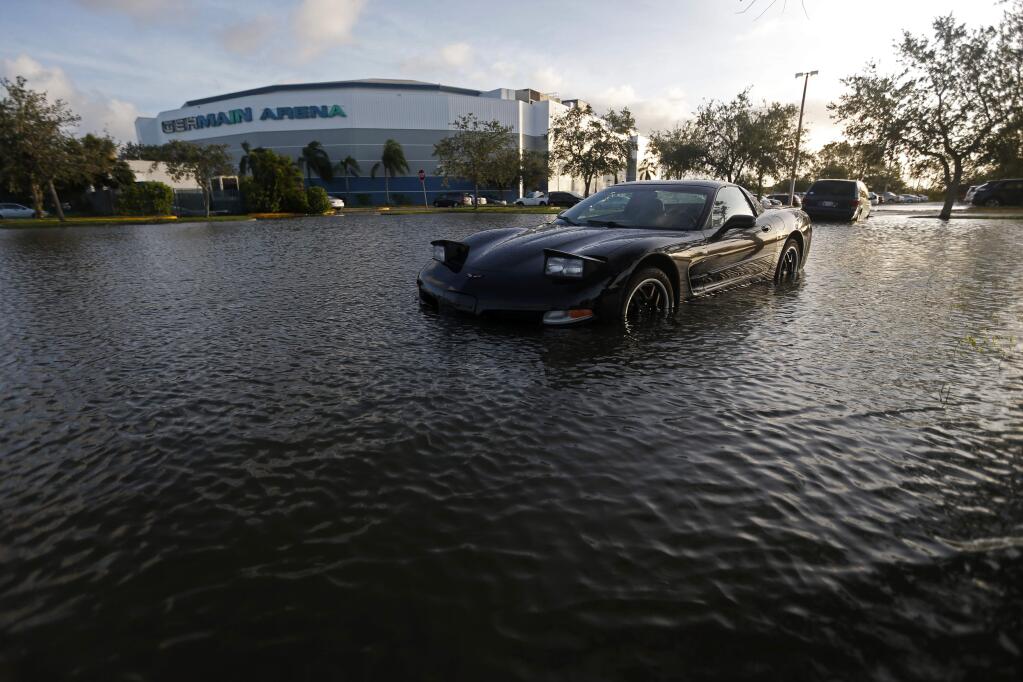 A car sits in a flooded parking lot outside the Germain Arena, which was used as an evacuation shelter for Hurricane Irma, which passed through yesterday, in Estero, Fla., Monday, Sept. 11, 2017. (AP Photo/Gerald Herbert)