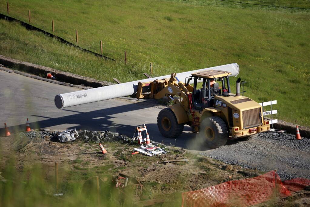 Construction workers continue to unload pipe from a flatbed trailer truck after one of the pipe pieces rolled over and killed a 33-year-old construction worker southwest of the Petaluma Blvd S exit of Hwy 101 in Petaluma, on Wednesday, April 15, 2015. (BETH SCHLANKER/ The Press Democrat)
