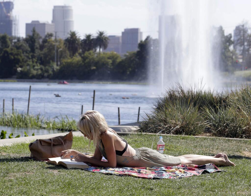 Corrie Nantes, an English tourist who lives in Australia, enjoys the sun next the Echo Park Lake in Los Angeles, on Tuesday, Sept. 8, 2015. Southern California will see dangerously high temperatures this week and a chance of thunderstorms and flooding in the mountains as a building high-pressure system delivers a late-summer scorching, forecasters said Tuesday. Excessive heat warnings were issued into Thursday night in many areas, with highs expected to reach 102 to 106 degrees in the valleys and lower mountain elevations. (AP Photo/Nick Ut)