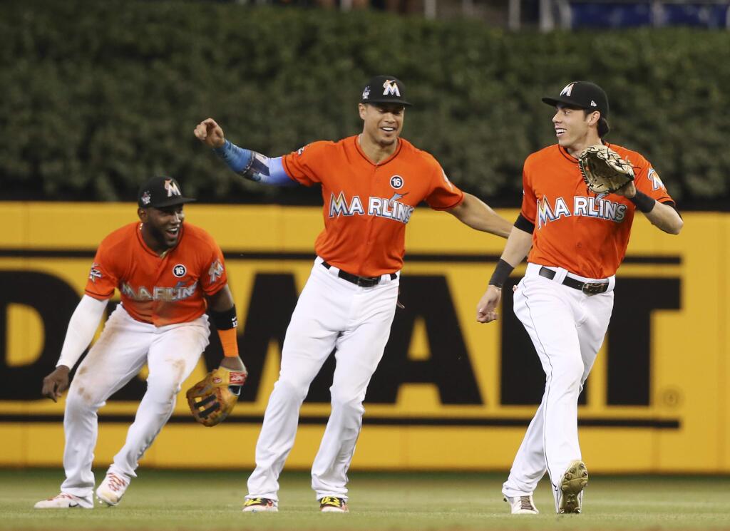 Miami Marlins center fielder Christian Yelich, right, right fielder Giancarlo Stanton, center, and left fielder Marcell Ozuna, left, celebrate after they defeated the Colorado Rockies in a baseball game, Sunday, Aug. 13, 2017, in Miami. (AP Photo/Wilfredo Lee)