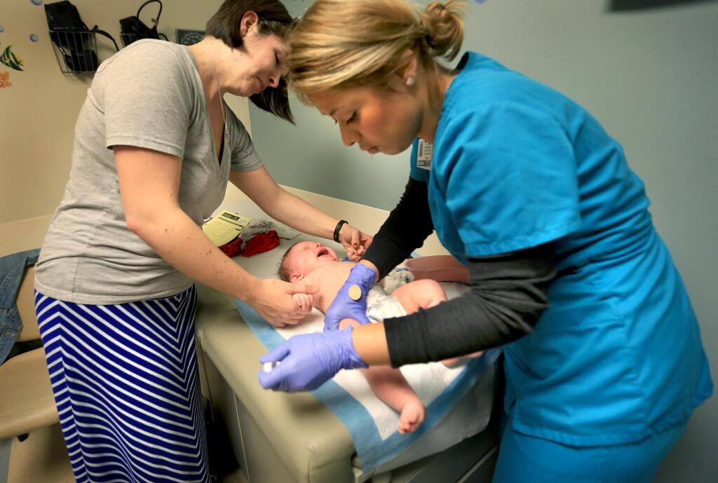 Kaiser LVN Michelle Quezada, right, gives 4-month-old Emery Harper her second vaccination series as Emery's mother, Christy Harper, helps hold her daughter still on Monday Jan. 19, 2015 at Kaiser in Santa Rosa. (Kent Porter / Press Democrat) 2015