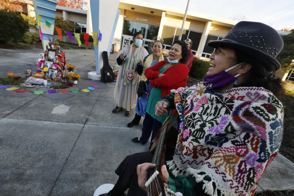 Renee Saucedo, right, the program director at ALMAS, plays the guitar and leads a song during a Día de los Muertos event to honor undocumented immigrants who have died from COVID-19. The event took place in front of the Sonoma County Board of Supervisors  in Santa Rosa, Calif., on Tuesday, November 2, 2021.(Beth Schlanker/The Press Democrat)