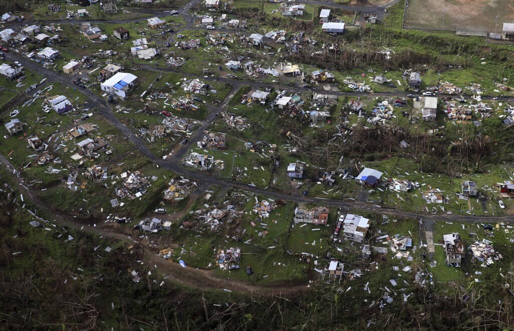 FILE - In this Sept. 28, 2017 file photo, homes and other buildings destroyed by Hurricane Maria lie in ruins in Toa Alta, Puerto Rico. Puerto Rico's governor on Monday, Dec. 18, 2017 ordered authorities to review all deaths reported since Hurricane Maria hit nearly three months ago amid accusations that the U.S. territory has vastly undercounted storm-related deaths. (AP Photo/Gerald Herbert, File)