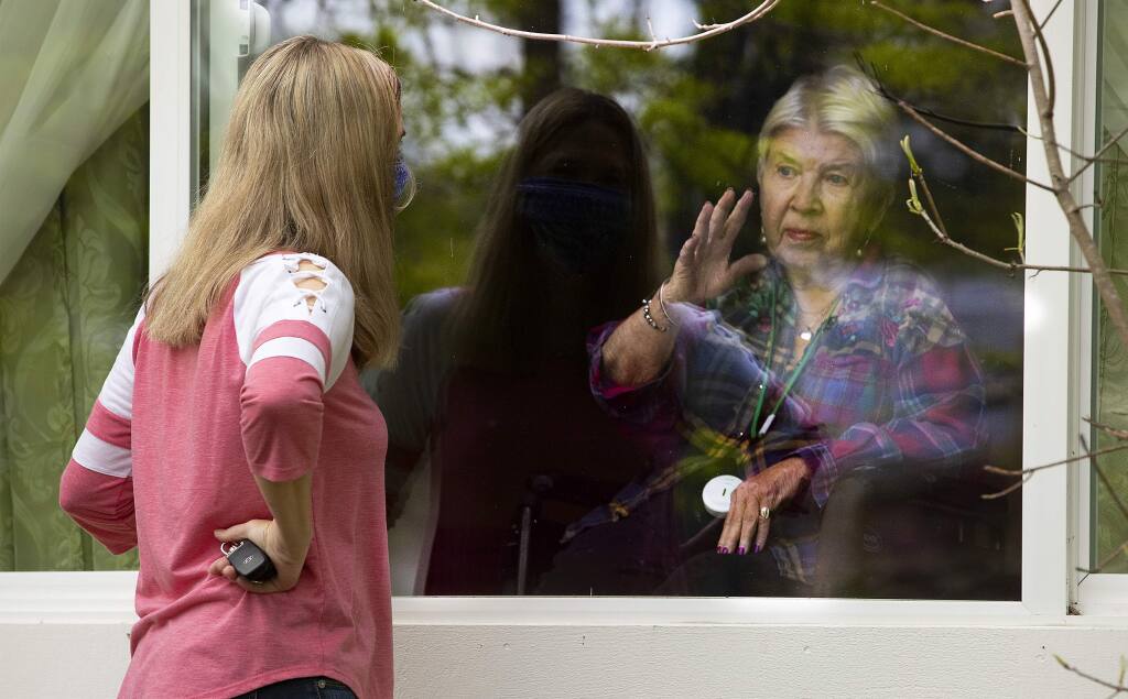 Colette Owens speaks to her mother, June Biava, through the window of Family House, a memory care home in Rohnert Park, in May 2020. Owens has staff open a side window so they can talk about doing their nails and the inability to get haircuts during the pandemic. (John Burgess / The Press Democrat)