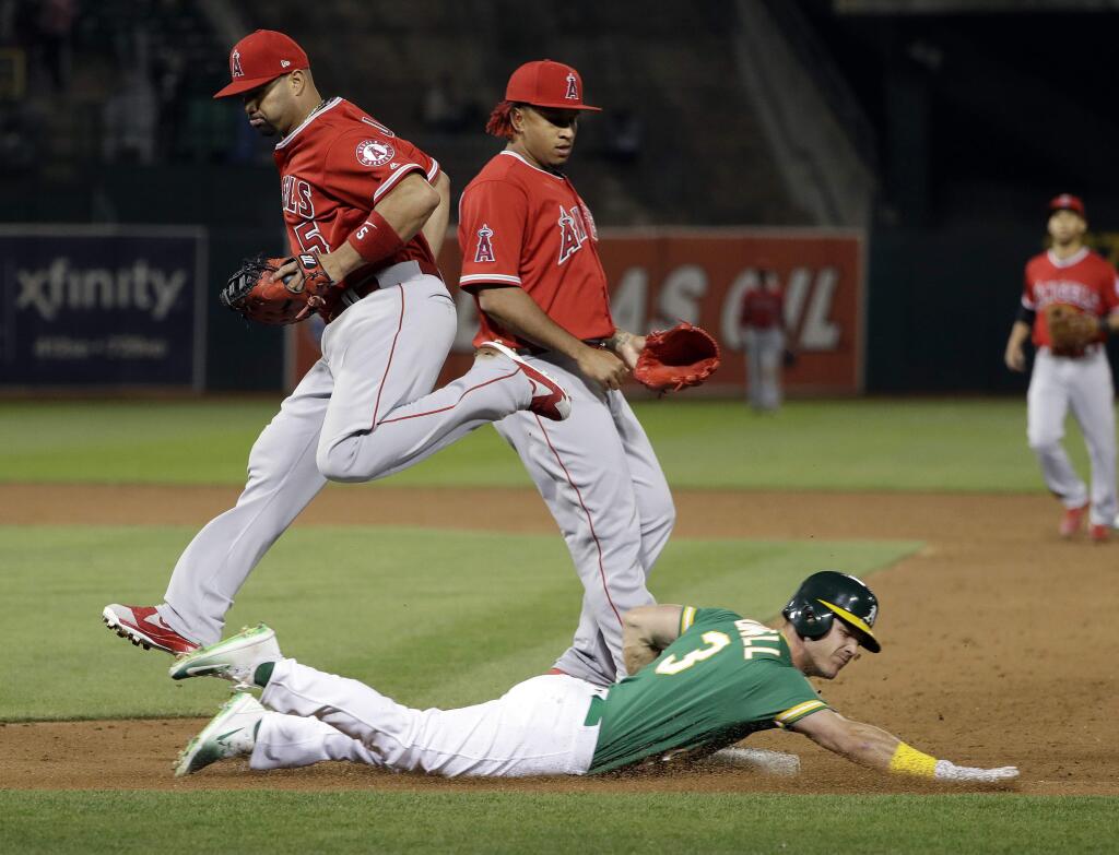 Los Angeles Angels first baseman Albert Pujols, top left, forces out the Oakland Athletics' Boog Powell, bottom, at first base after a ground ball during the eighth inning Friday, March 30, 2018, in Oakland. (AP Photo/Marcio Jose Sanchez)