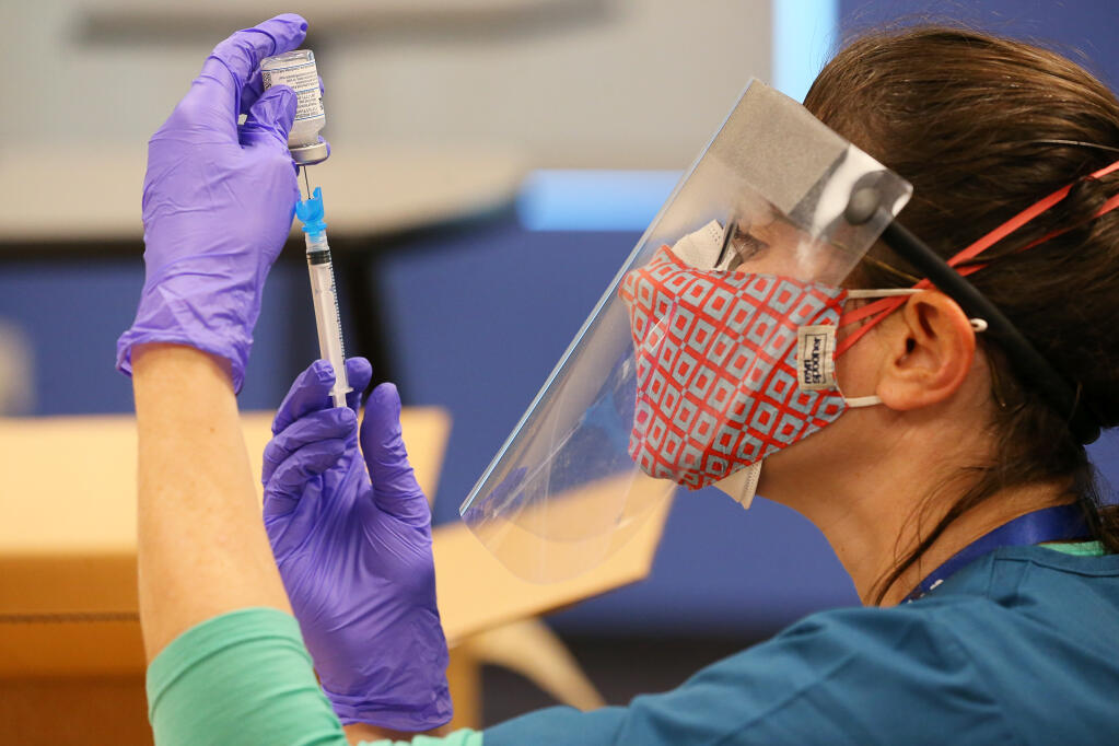Sonoma County Office of Education registered nurse Sarah Mai prepares a syringe with the Moderna COVID-19 at Rancho Cotate High School in Rohnert Park on Monday, Feb. 8, 2021.  (Christopher Chung/ The Press Democrat)