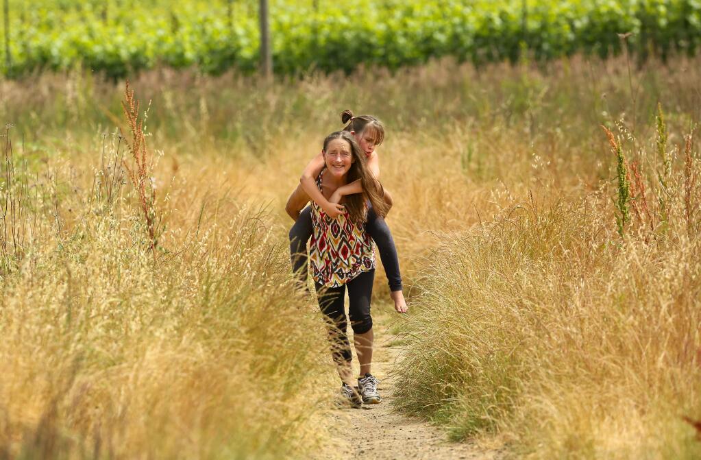 Cynthia Johnson gives a piggyback ride to her granddaughter Verona Mitchell, 7, along the West County Regional Trial between Forestville and Graton on Tuesday afternoon, May 30, 2017. The path is one of the six new walks added to the Sonoma County Regional Parks' fourth annual trails challenge. (John Burgess/The Press Democrat)
