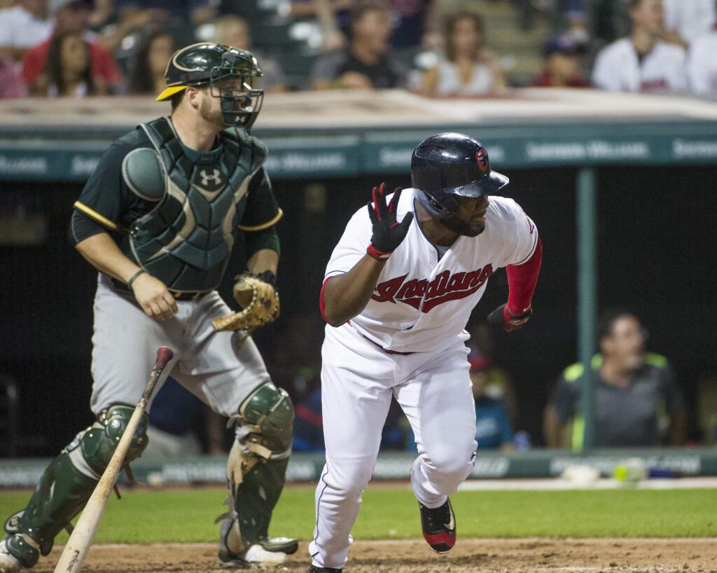 Cleveland Indians pinch hitter Abraham Almonte, right, hits a single off Oakland Athletics starter Kendall Graveman as Athletics catcher Stephen Vogt watches during the seventh inning in Cleveland, Friday, July 29, 2016. (AP Photo/Phil Long)
