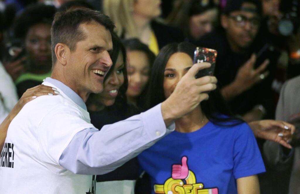 Jim Harbaugh takes a selfie with first lady Michelle Obama, center, and Grammy award winner Ciara during the citywide College Signing Day, Friday, May 1, 2015, at Wayne State University in Detroit. (Carlos Osorio / Associated Press)