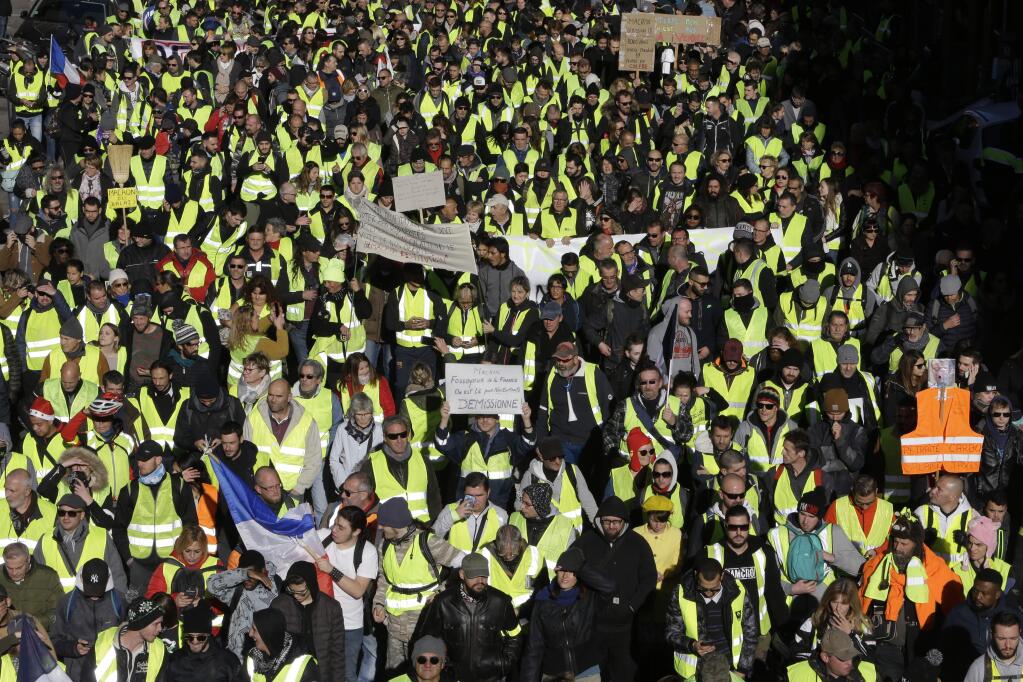 Demonstrators wearing yellow vests march Saturday, Dec. 8, 2018 in Marseille, southern France. The grassroots movement began as resistance against a rise in taxes for diesel and gasoline, but quickly expanded to encompass frustration at stagnant incomes and the growing cost of living. (AP Photo/Claude Paris)