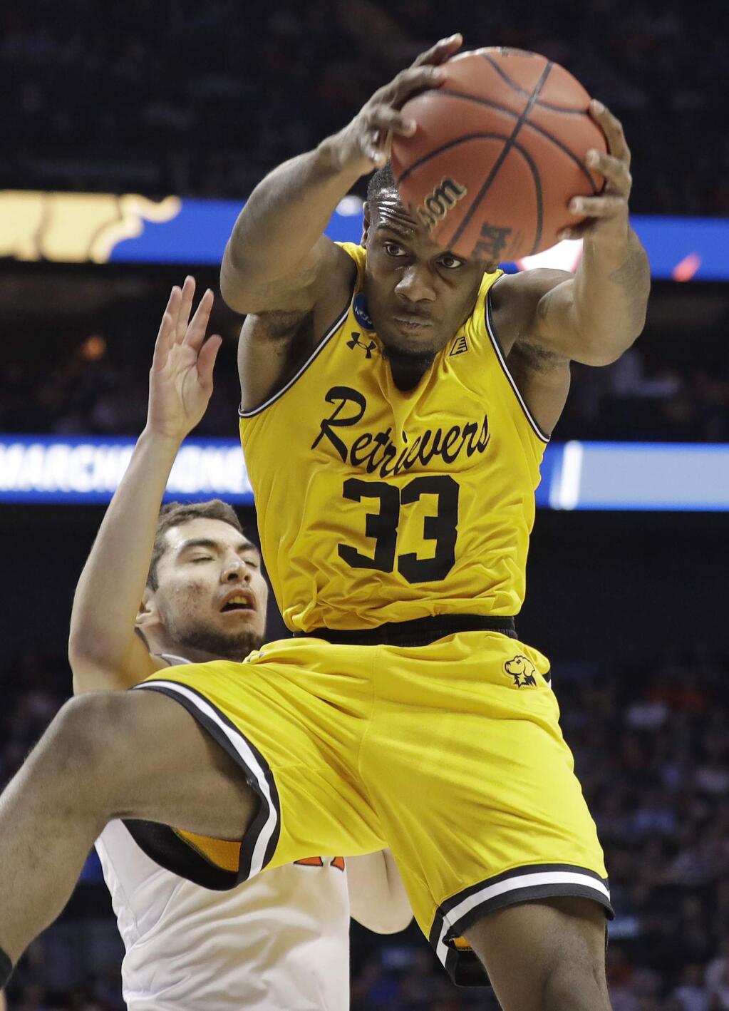 UMBC's Arkel Lamar (33) grabs a rebound in front of Virginia's Ty Jerome during the first half of a first-round game in the NCAA men's college basketball tournament in Charlotte, N.C., Friday, March 16, 2018. (AP Photo/Gerry Broome)