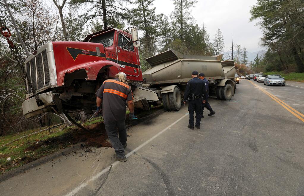 Emergency crews remove a semi-truck involved in a head-on fatal accident with a Volkswagen sedan on Petrified Forest Rd. west of Calistoga on Tuesday afternoon, December 19, 2017. (photo by John Burgess/The Press Democrat)