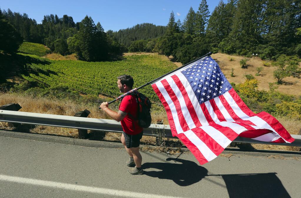 Army veteran Ryan Tonkinson of Oakley walks with an American flag along Petrified Forest Rd. out of Calistoga towards Santa Rosa on Thursday afternoon. Tonkinson was part of the Old Glory Relay from Washington State to Florida. (John Burgess/The Press Democrat)