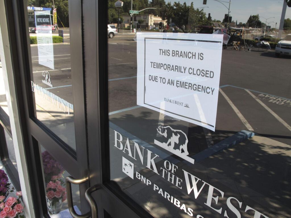 This Wednesday July 16, 2014 image provided by the Stockton Police Department shows a closed sign on a Stockton, Calif. bank after a robbery. Three bank robbers took three women hostage as they made a getaway and waged a high-speed gunbattle with police that left three people dead and cars and homes riddled with bullets, authorities said. (AP Photo/Stockton Police Department)
