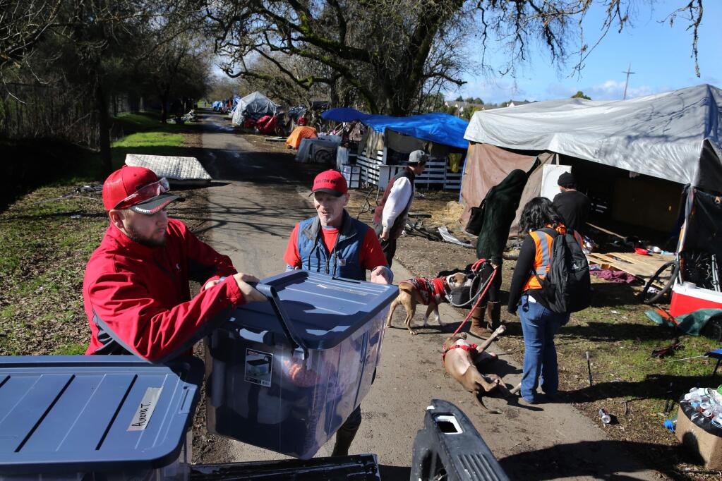 Andre Maring, left, and Darren Moffet, employees of Belfor Property Restoration, help an 18-year-old woman load boxes of her belongings as she moves from her campsite on the Joe Rodota Trail to a temporary camp at the Los Guilicos Juvenile Justice Center site in Santa Rosa on Sunday, Jan. 26, 2020. (Beth Schlanker / The Press Democrat)