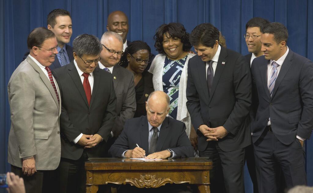 Gov. Jerry Brown signs legislation that will automatically enroll millions of private-sector workers in retirement saving account. The bill, SB-1234, by Senate President Pro Tem Kevin de Leon, D-Los Angeles, third from right, creates a state-run retirement program for nearly 7 million who don't have an employer-sponsored plan. (RICH PEDRONCELLI / Associated Press)