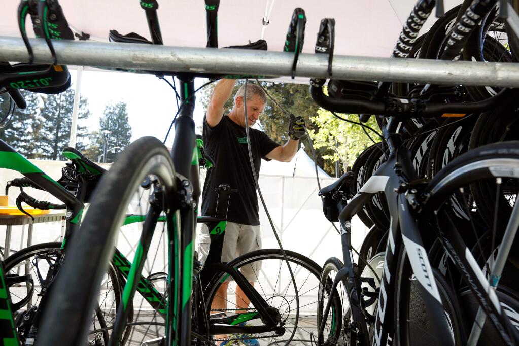 Jamie Lamar of Raceday Wheels secures the rental bicycles and wheels provided by his company in the Ironman Village at Old Courthouse Square in Santa Rosa, California, on Wednesday, July 25, 2018. (Alvin Jornada / The Press Democrat)