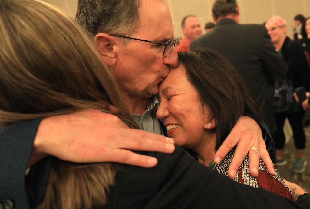 Judy K. Sakaki, President of Sonoma State University is embraced by her husband Patrick McCallum and Emily Hinton, left, the student representative to the Sonoma State University Board of Trustees, Wednesday Oct. 18, 2017 prior to a ceremony honoring first responders. Sakaki and her husband were rescued by Santa Rosa firefighters in Fountaingrove during the Tubbs fire last week. (Kent Porter / The Press Democrat) 2017