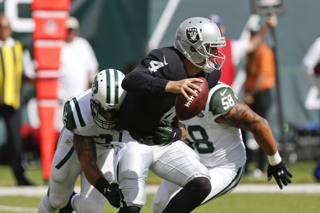 Oakland Raiders quarterback Derek Carr (4) looks to pass as he is sacked by New York Jets' Dawan Landry (26) during the second half of an NFL football game Sunday, Sept. 7, 2014, in East Rutherford, N.J. (AP Photo/Seth Wenig)