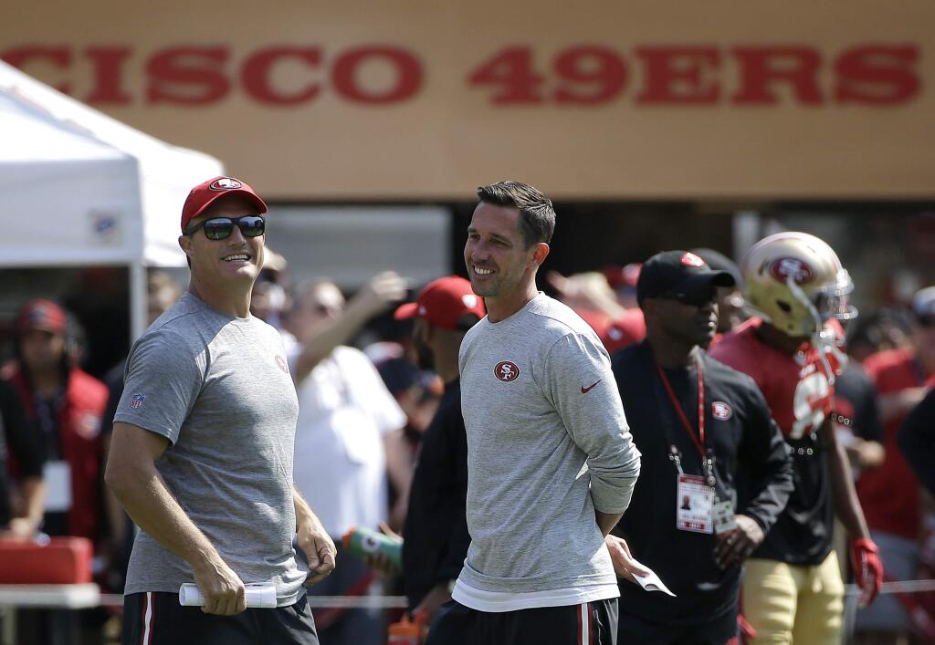 San Francisco 49ers head coach Kyle Shanahan, center, laughs with general manager John Lynch during training camp in Santa Clara, Saturday, Aug. 5, 2017. (AP Photo/Jeff Chiu)