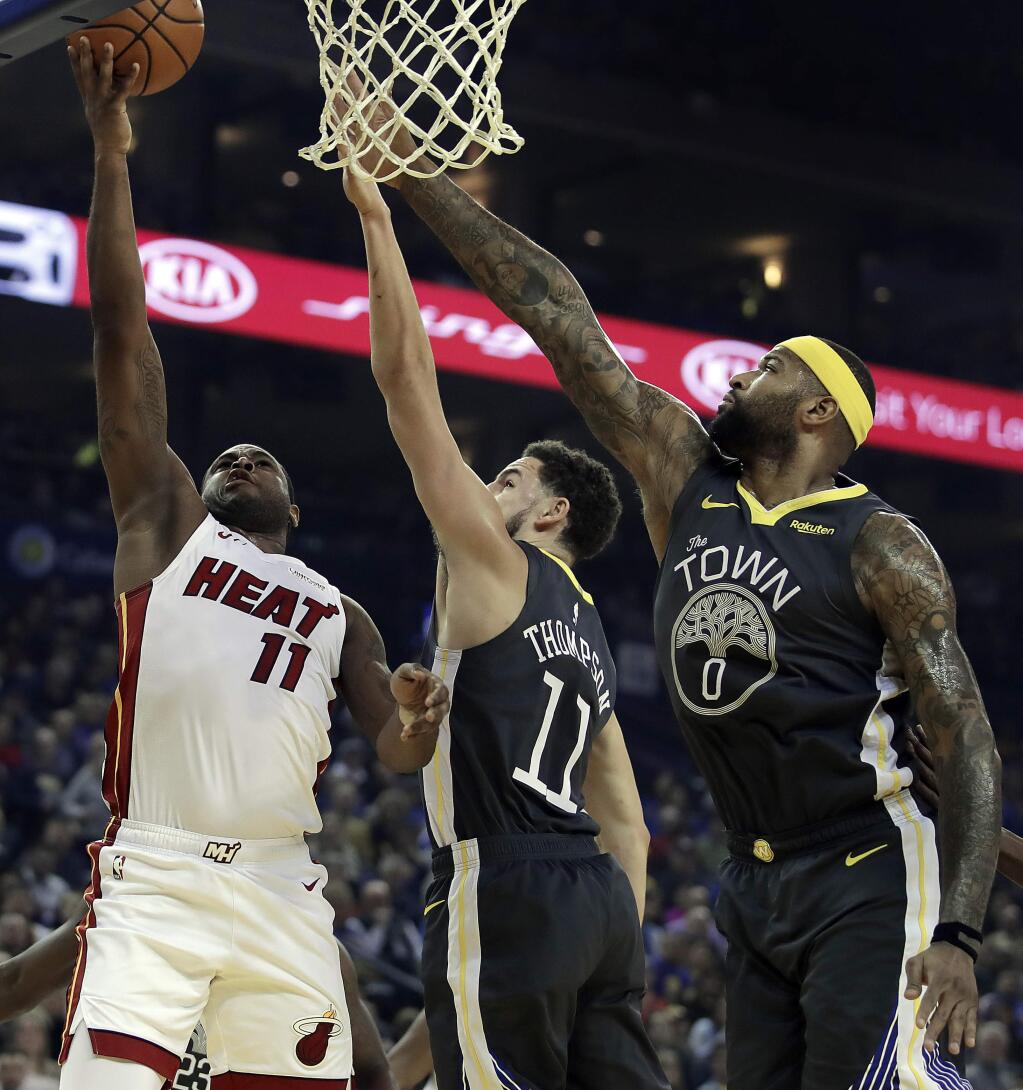 Miami Heat guard Dion Waiters, left, shoots against Golden State Warriors' Klay Thompson, center, and DeMarcus Cousins (0) during the first half of an NBA basketball game day, Feb. 10, 2019, in Oakland, Calif. (AP Photo/Ben Margot)