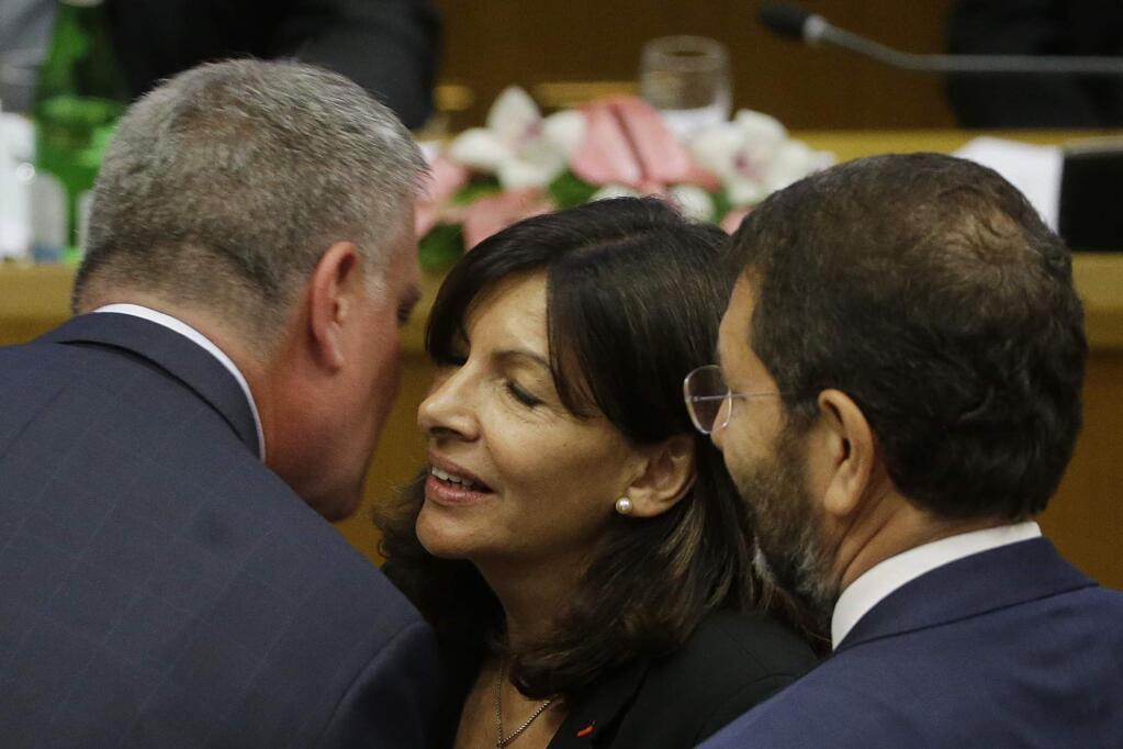 New York Mayor Bill de Blasio, left, shares a word with Paris Mayor Anne Hidalgo, center, and Rome Mayor Ignazio Marino during a conference on Modern Slavery and Climate Change in the Synod Hall at the Vatican, Tuesday, July 21, 2015. Dozens of environmentally friendly mayors from around the world are meeting at the Vatican this week to bask in the star power of eco-Pope Francis and commit to reducing global warming and helping the urban poor deal with its effects. (AP Photo/Gregorio Borgia)