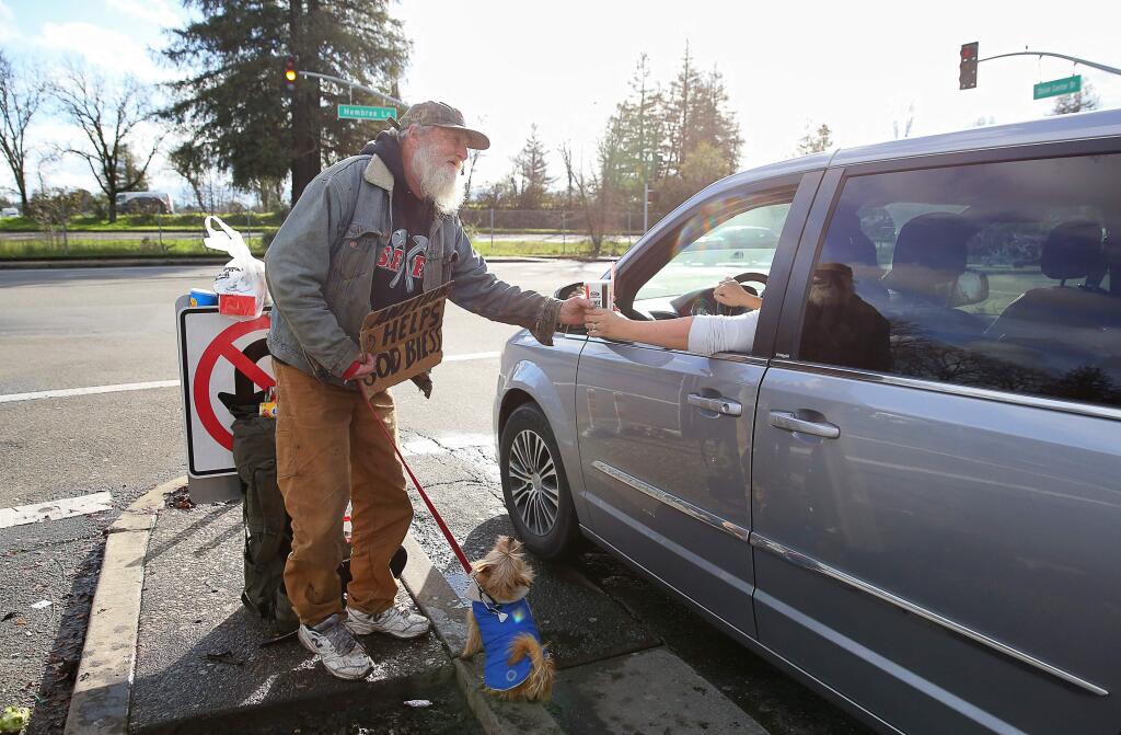 Christopher Chung / The press DemocratDavid Hudson, 64, with his dog Festus, accepts a drink from a motorist, while panhandling in the median on MacFarlane Way at Hembree Lane, in Windsor on Monday.