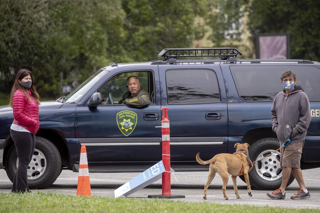 Park police and neighboring residents survey the damage in Golden Gate Park, Saturday, June 20, 2020, after statues of Junipero Serra, U.S. Grant and Francis Scott Key were toppled and graffiti was spray painted over many walls and pedestals. (Karl Mondon/Bay Area News Group via AP)