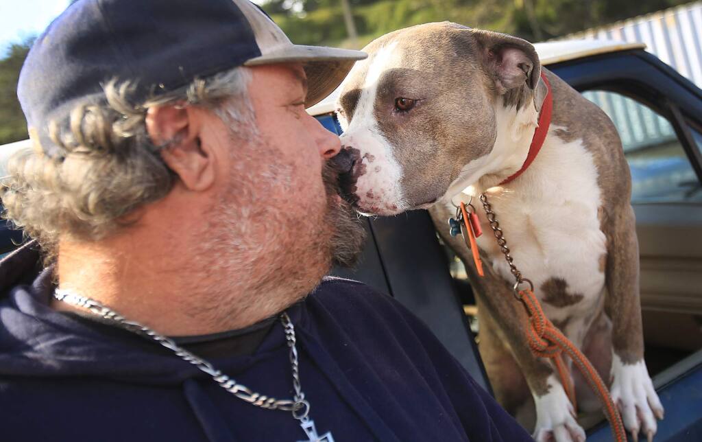 Michael 'Moose' Sartori a deckhand on the Bernice and his dog Zeke, share a light moment at Spud Point Marina in Bodega Bay, Tuesday Jan. 13, 2016 as Sartori waits for word on the ongoing crab closure. (Kent Porter / Press Democrat) 2016