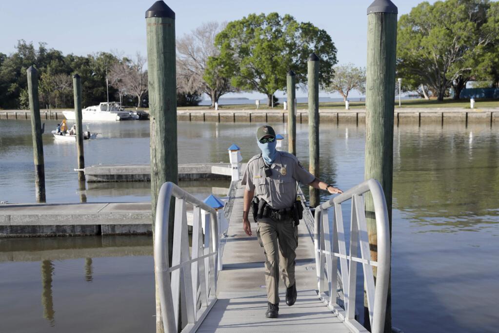FILE - In this May 4, 2020, file photo, Park ranger Tyler Gagat wears a protective face mask as he monitors activity at the Flamingo boat ramp during the new coronavirus pandemic in Everglades National Park in Florida, as the park gradually reopens to the public in phases. As the coronavirus pandemic continues, the National Park Service is testing public access at several parks across the nation (AP Photo/Lynne Sladky, File)