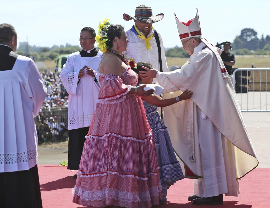 A child reaches out to embrace Pope Francis in the offertory during a Mass at the Maquehue Air Base, in Temuco, Chile, Wednesday, Jan. 17, 2018. Francis is paying homage to Chileans who were tortured or killed at the air base. Francis said the area is 'the site of grave violations of human rights,' and that the Mass was being offered for all those who have suffered or died. (AP Photo/Alessandra Tarantino)
