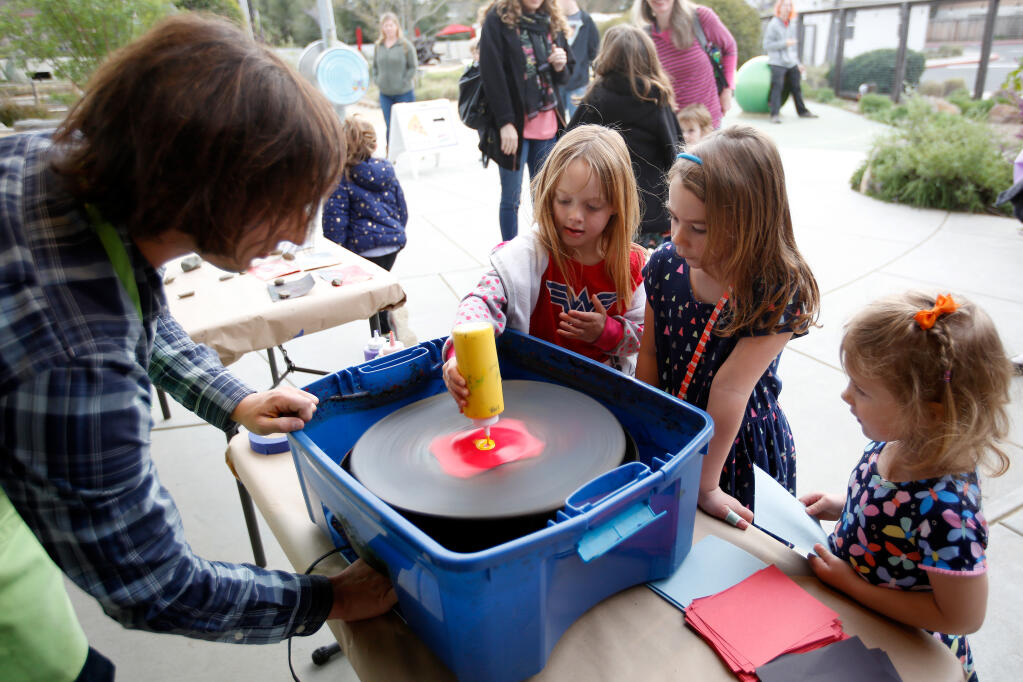 Elyssa Wright, 5, center, and her friends Amelia Supinger, 4, and Alexis Kracht, 3, far right, make spin art with help from museum programs coordinator Chris Berg, left, during a special night for Coffey Park fire survivors at the Children's Museum of Sonoma County, in Santa Rosa, California, on Friday, March 9, 2018. (Alvin Jornada / The Press Democrat)