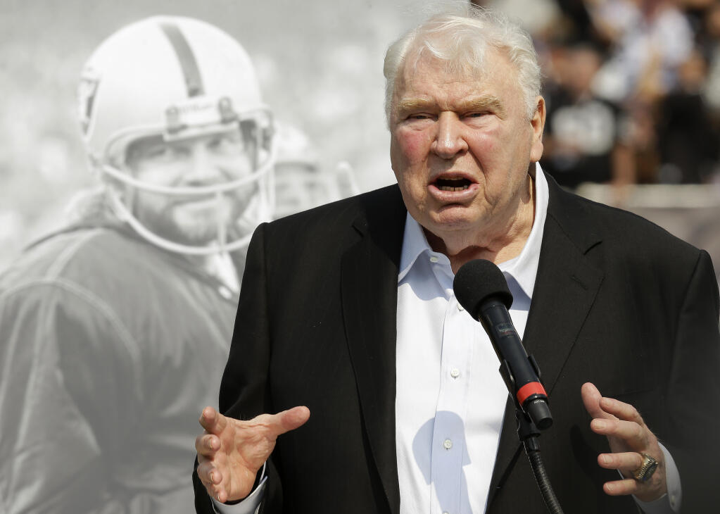 FILE - Former Oakland Raiders head coach John Madden speaks about former quarterback Ken Stabler, pictured at rear, at a ceremony honoring Stabler during halftime of an NFL football game between the Raiders and the Cincinnati Bengals in Oakland, Calif., Sept. 13, 2015. John Madden, the Hall of Fame coach turned broadcaster whose exuberant calls combined with simple explanations provided a weekly soundtrack to NFL games for three decades, died Tuesday, Dec. 28, 2021, the NFL said. He was 85. (AP Photo/Ben Margot, File)